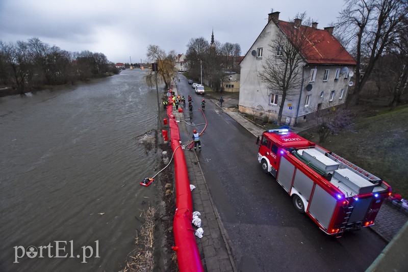 Elbląg, Strażacy i pracownicy Centrum Zarządzania Kryzysowego rozkładają rękawy przeciwpowodziowe przy bulwarze Zygmunta Augusta