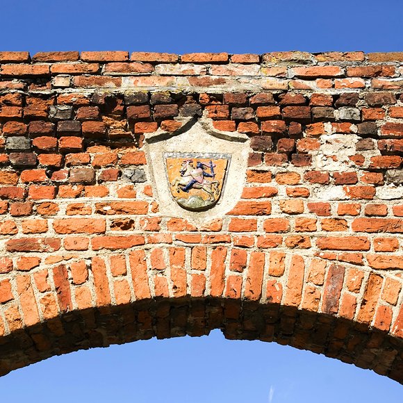 Fragment murów obronnych i herb miasta Pasłęka.