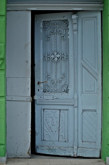 Ogrodniki - okruchy dawnego piękna. Drzwi wejściowe do budynku mieszkalnego przy sklepie w Ogrodnikach. Wielokrotnie przemalowane, bez oryginalnej klamki i z dodanym dziwnym skoblem. (Kwiecień 2014)