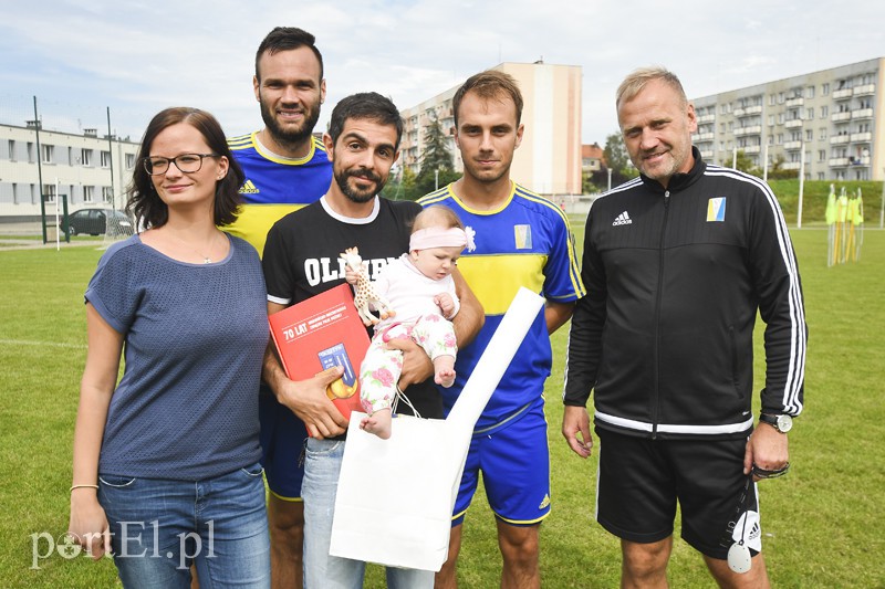 Elbląg, Agata i Bizio wraz z malutką Olimpią oraz upominkami od klubu. Z tyłu piłkarze:Tomasz Lewandowski oraz Michał Ressel, a także Adam Boros, trener drużyny