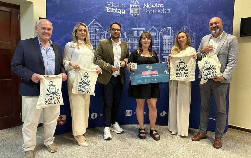 Elbląg, Zwycięskie logo na torbach promocyjnych projektu. Nagrodę dla pani Elżbiety (w środku) wręczyli przedstawiciele poszczególnych samorządów Elbląg, Zwycięskie logo na torbach promocyjnych projektu. Nagrodę dla pani Elżbiety (w środku) wręczyli przedstawiciele poszczególnych samorządów