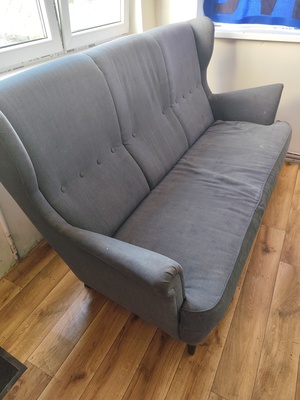 Elbląg Używana, nierozkładana sofa STRANDMON marki IKEA. Mebel jest w szarym kolorze, posiada wygodne pikowane